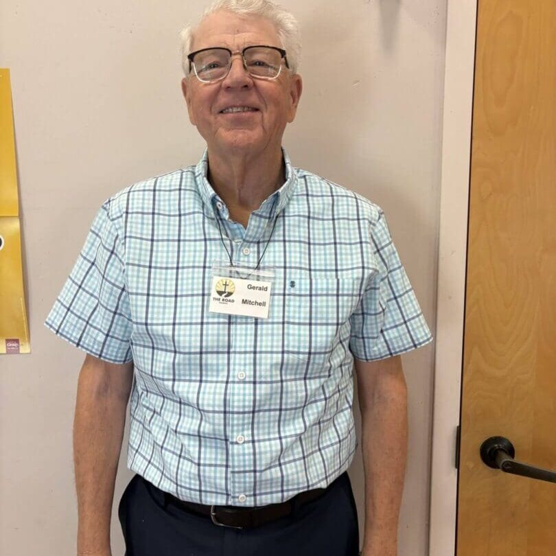 Smiling man wearing glasses and checkered shirt.