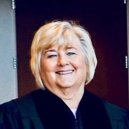 Smiling person in formal black attire.