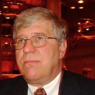 Man in suit with glasses indoors.